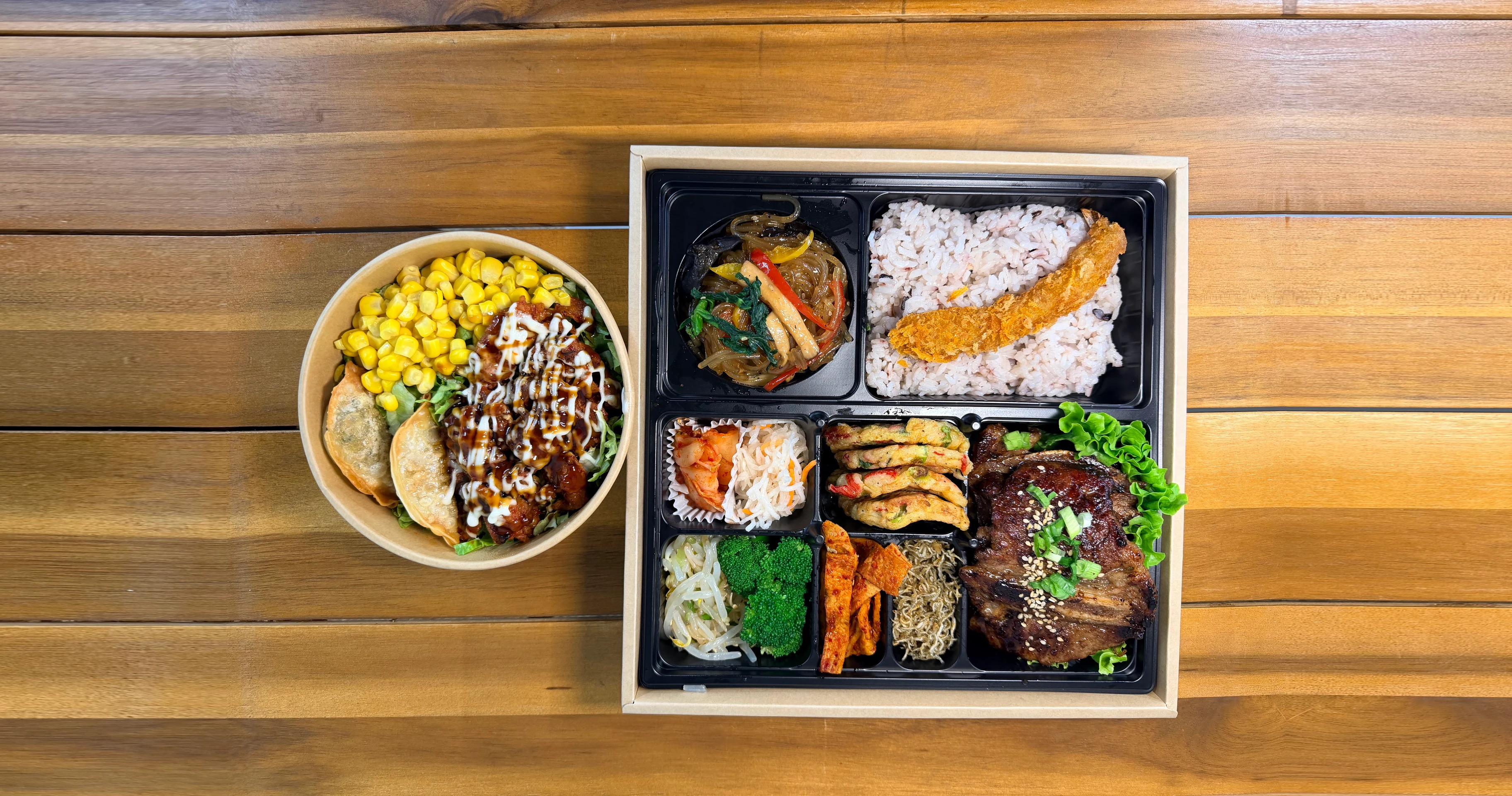 LA galbi dosirak beside a cupbab bowl on a wooden table
