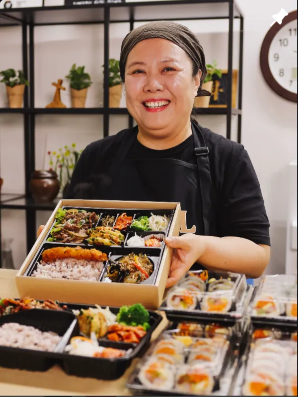 Owner Heesun Jang holding a Seoul Spoon dosirak